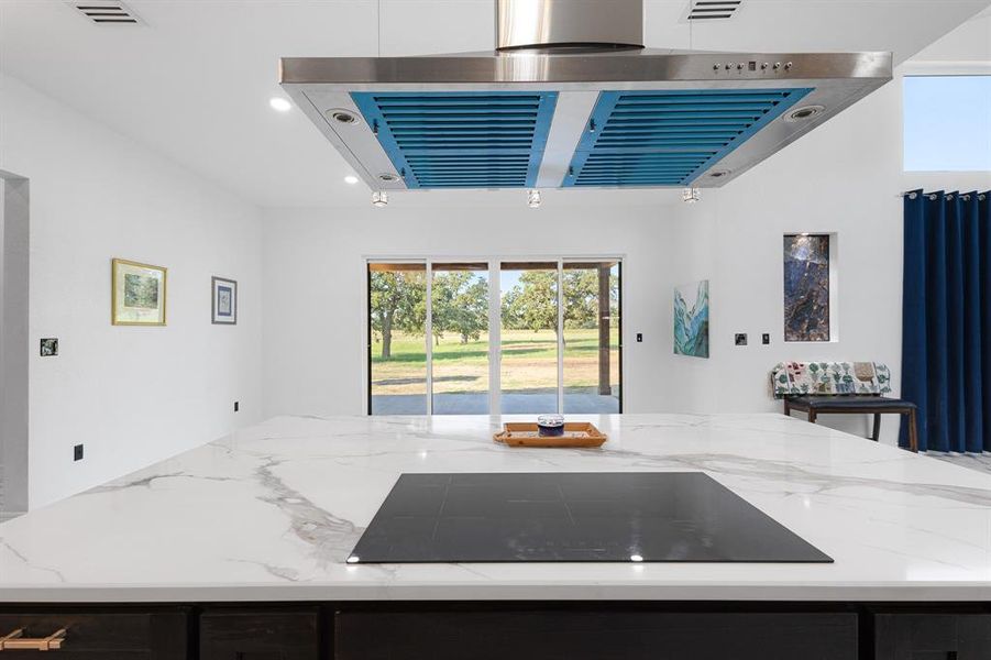 Kitchen with range hood, healthy amount of natural light, black electric cooktop, light stone counters, and recessed lighting