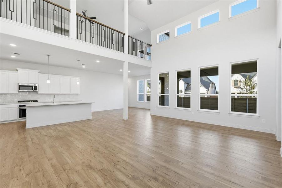 Unfurnished living room featuring light wood-style floors and a high ceiling