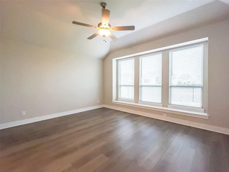 Unfurnished room featuring dark wood finished floors, lofted ceiling, and ceiling fan Unfurnished room featuring dark wood finished floors, lofted ceiling, and ceiling fan