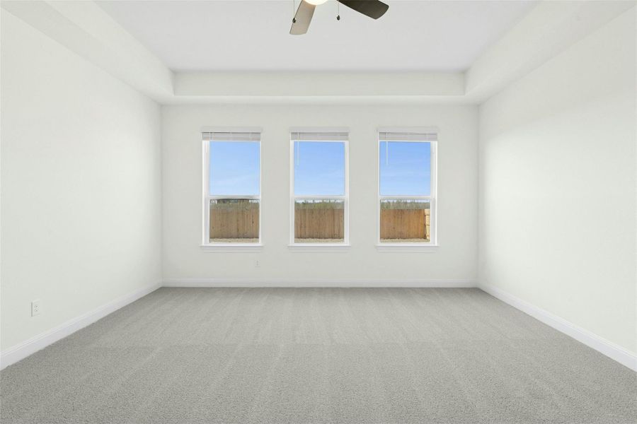 Spare room featuring light colored carpet, a ceiling fan, and plenty of natural light