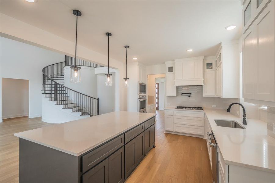 The kitchen features a large island with dark cabinetry, light countertops, and three pendant lights