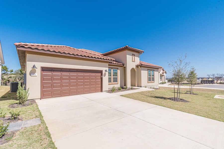 Mediterranean / spanish house featuring driveway, a front lawn, an attached garage, and stucco siding