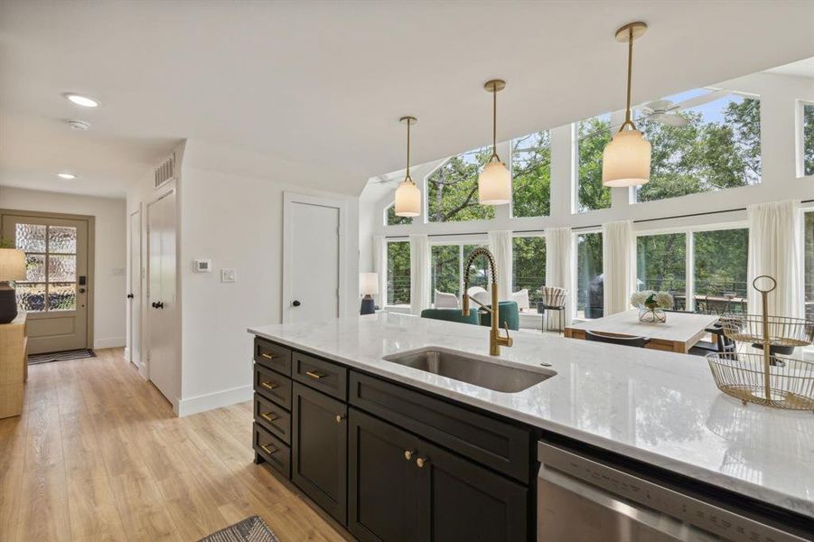 Kitchen with decorative light fixtures, sink, plenty of natural light, and light hardwood / wood-style flooring