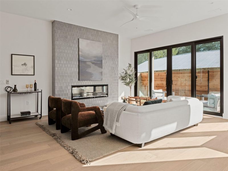 Living room with light wood-style floors, a fireplace, and a ceiling fan