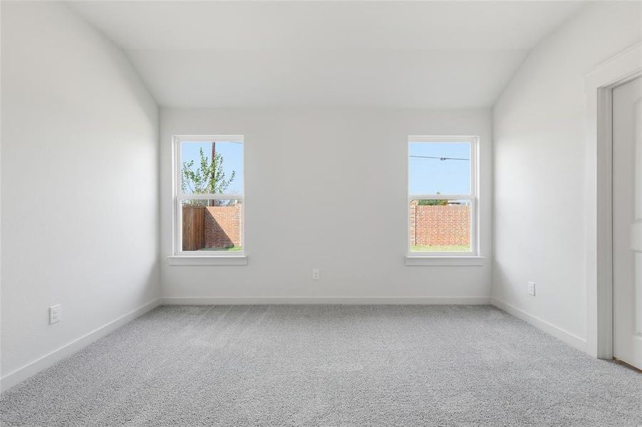 Carpeted spare room featuring vaulted ceiling and healthy amount of natural light Carpeted spare room featuring vaulted ceiling and healthy amount of natural light