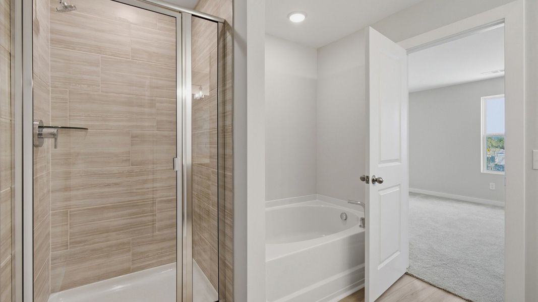 Bathtub next to shower in primary bathroom