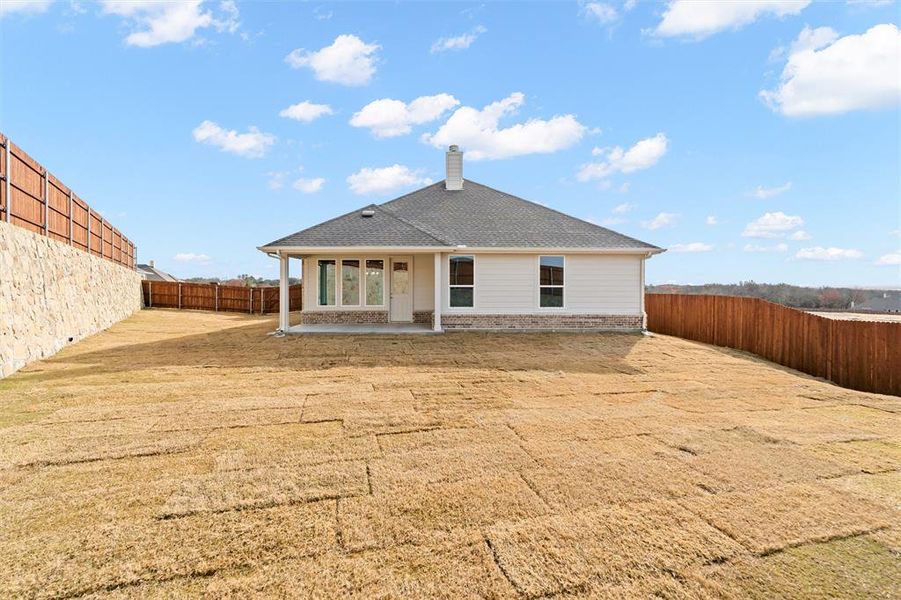 Rear view of house with a patio, a fenced backyard, a chimney, and a shingled roof