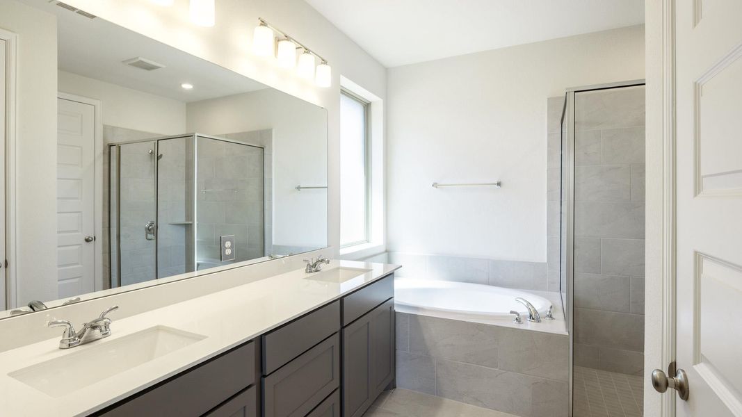 Full bath featuring double vanity, a bath, and a stall shower Full bath featuring double vanity, a bath, and a stall shower
