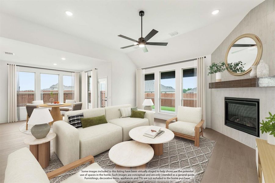 Open living room with vaulted ceiling, ceiling fan, tile fireplace, and hardwood floors open to dining area Open living room with vaulted ceiling, ceiling fan, tile fireplace, and hardwood floors open to dining area
