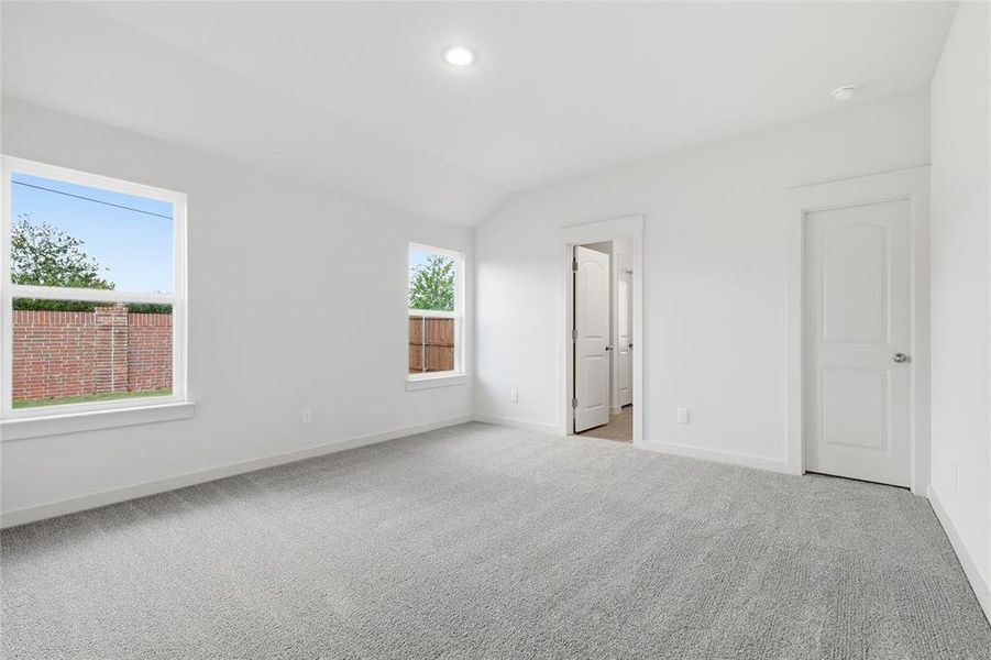 Unfurnished bedroom featuring light carpet and lofted ceiling Unfurnished bedroom featuring light carpet and lofted ceiling