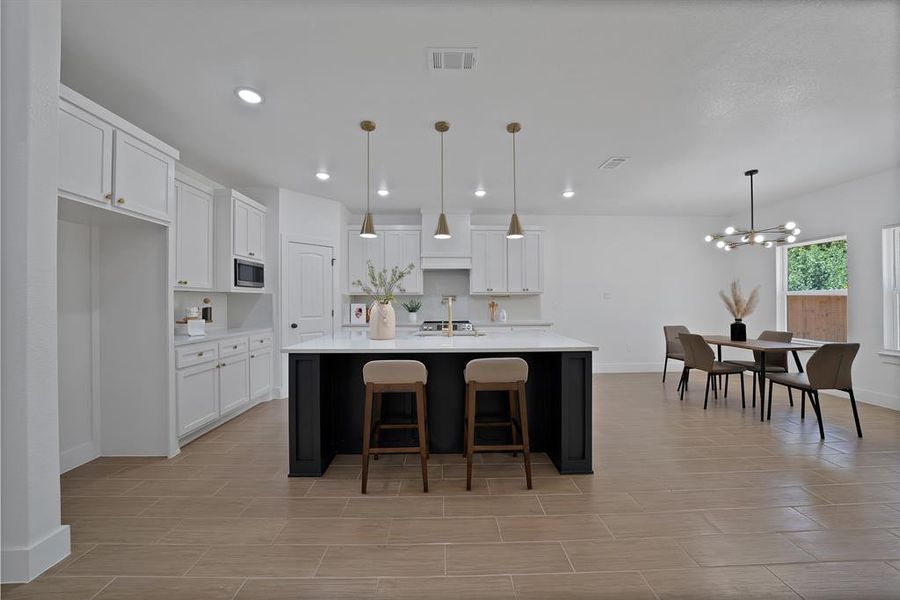 Kitchen featuring light countertops, white cabinetry, a chandelier, an island with sink, and recessed lighting