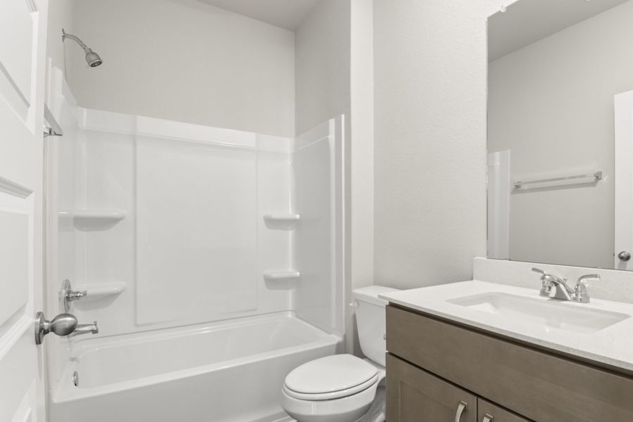 Image of a bathroom with a white shower and tub, brown cabinets, and a mirror