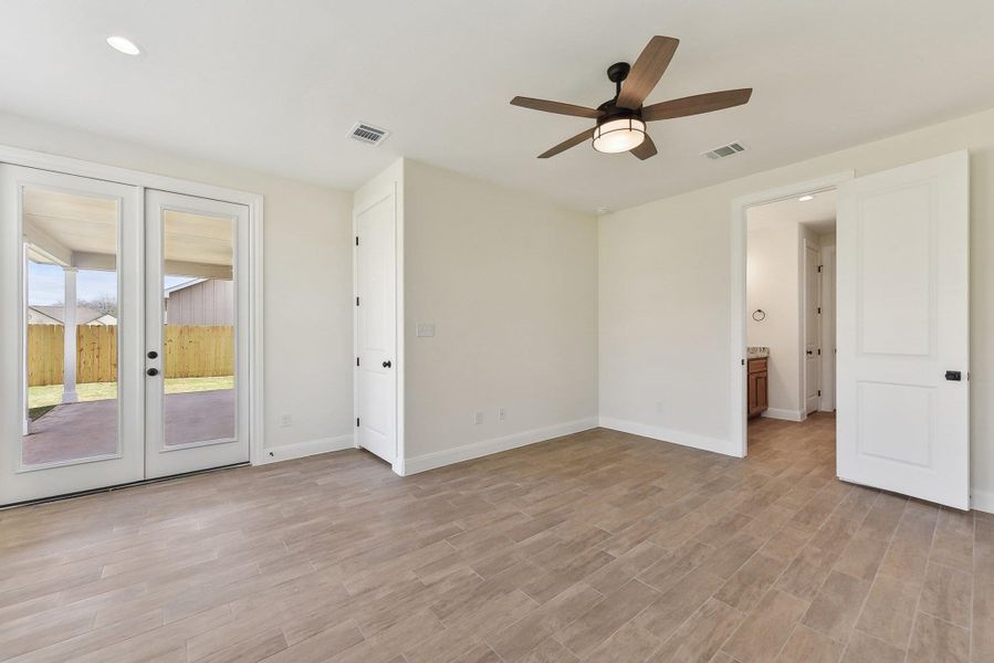 Unfurnished room with visible vents, light wood-style flooring, and french doors