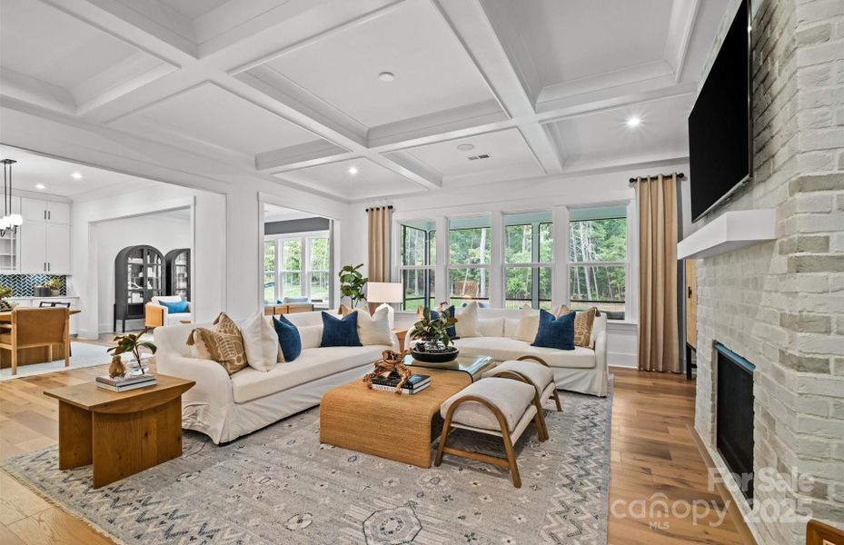 Bright and open gathering room with coffered ceiling and brick fireplace.  Representative photo