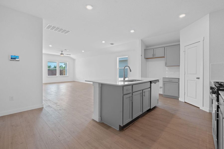 Kitchen with gray cabinetry, backsplash, recessed lighting, light wood-style floors, and a kitchen island with sink Kitchen with gray cabinetry, backsplash, recessed lighting, light wood-style floors, and a kitchen island with sink