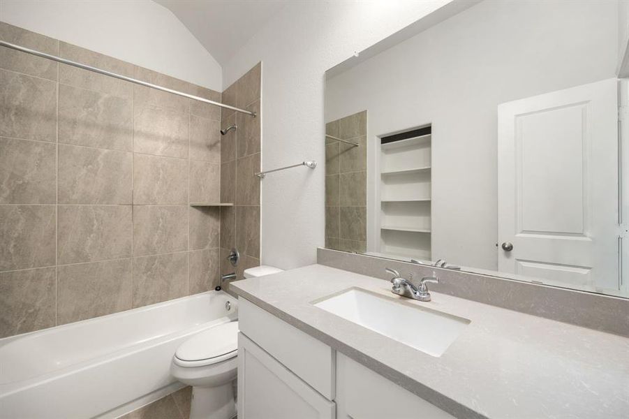 Secondary bathroom features light countertops and cabinets, neutral paint, shower/tub combo with tile surround, large mirror, tile floors, sleek fixtures and modern finishes, plenty of space to accommodate any visiting family or guests.