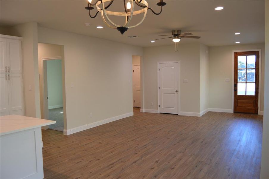 Unfurnished living room featuring dark hardwood / wood-style flooring and ceiling fan with notable chandelier