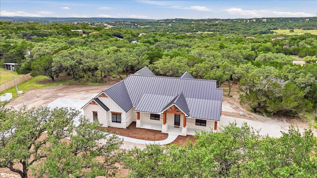 An aerial perspective reveals a newly constructed residence nestled amidst a verdant, rolling landscape.