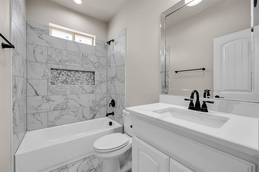 Full bathroom featuring vanity, tiled shower / bath, and toilet