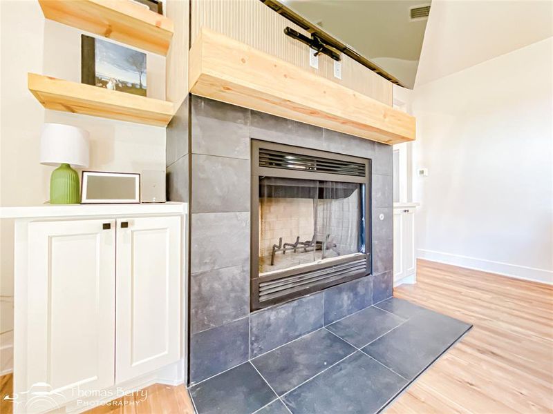 Modern wood burning fireplace accompanied by built-in cabinets for additional storage and decor.
