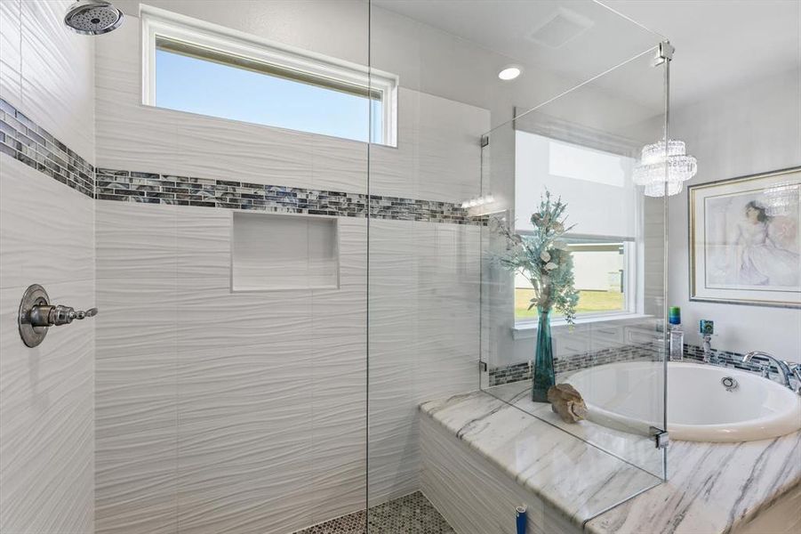 Bathroom featuring a built-in soaking tub with a marble-finish surround, a glass-enclosed shower, wave-textured wall tiles, a mosaic tile accent band, and an integrated shower niche