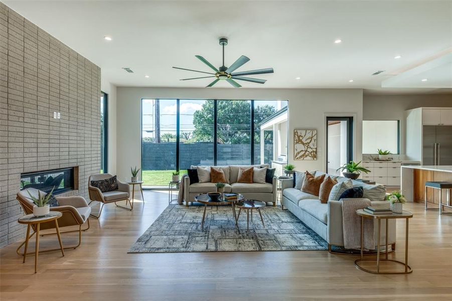 Living room with a fireplace, ceiling fan, and light hardwood / wood-style floors