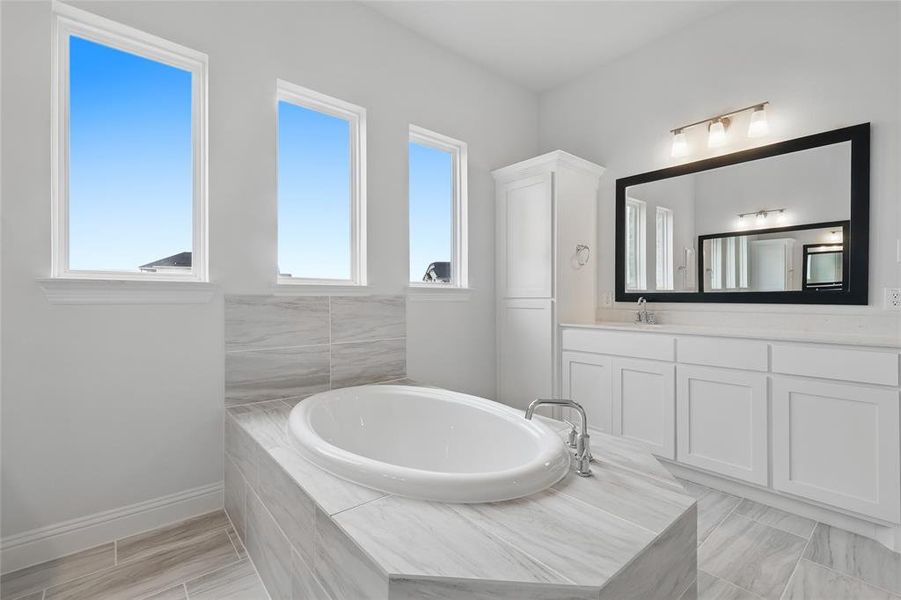 Full bathroom featuring baseboards, a bath, and vanity