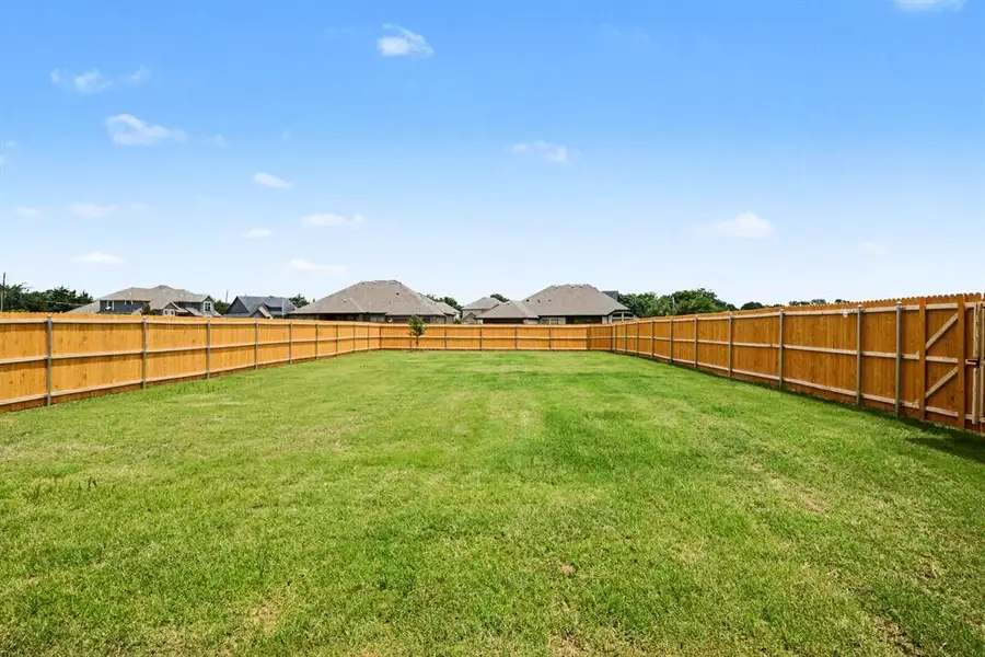 Expansive backyard featuring a manicured lawn, full perimeter wood fencing, and a side gate Expansive backyard featuring a manicured lawn, full perimeter wood fencing, and a side gate