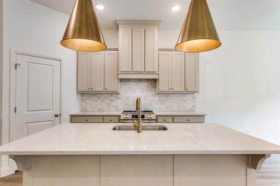 Kitchen with light stone countertops and a kitchen island with sink