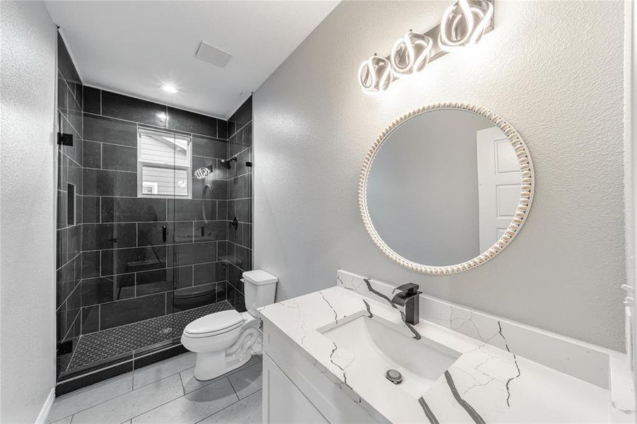 Bathroom with a textured wall, vanity, and a stall shower