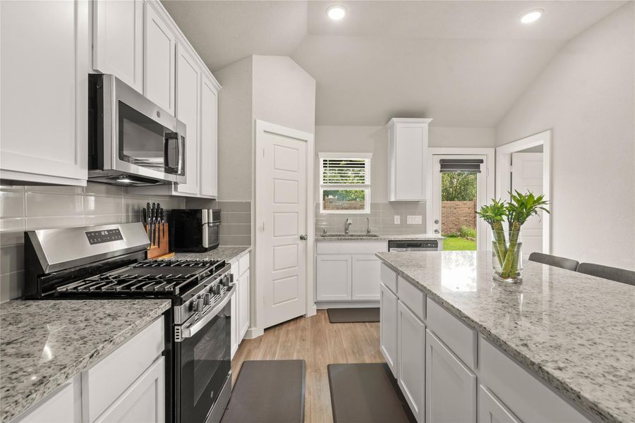 A modern tile backsplash and recessed lighting add a contemporary touch, while the open layout keeps the chef connected to guests and family.
