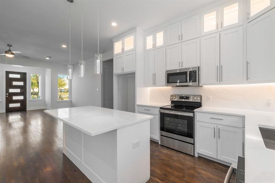 Kitchen featuring appliances with stainless steel finishes, dark hardwood / wood-style floors, a center island, white cabinetry, and ceiling fan