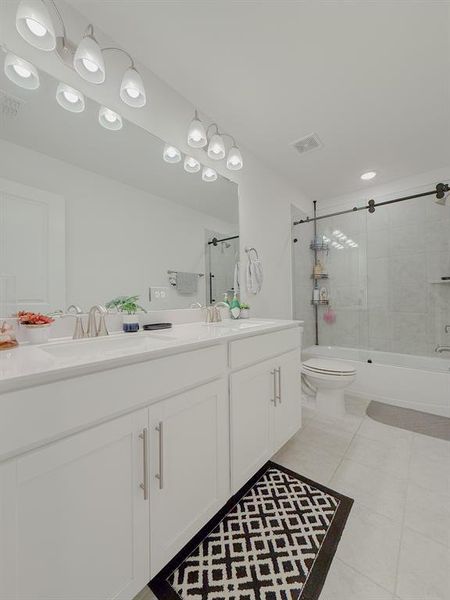 Bathroom featuring toilet, double vanity, a sink, and visible vents