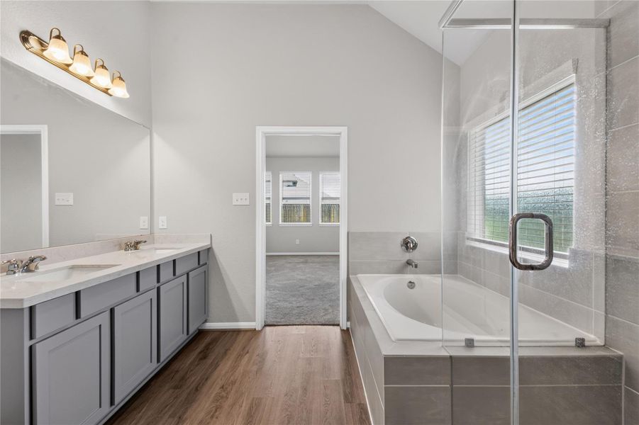 This bathroom features a modern design with a spacious glass-enclosed shower, dual sinks with a large mirror, and elegant wood flooring. The neutral color palette and ample lighting create a bright and inviting space. This bathroom features a modern design with a spacious glass-enclosed shower, dual sinks with a large mirror, and elegant wood flooring. The neutral color palette and ample lighting create a bright and inviting space.