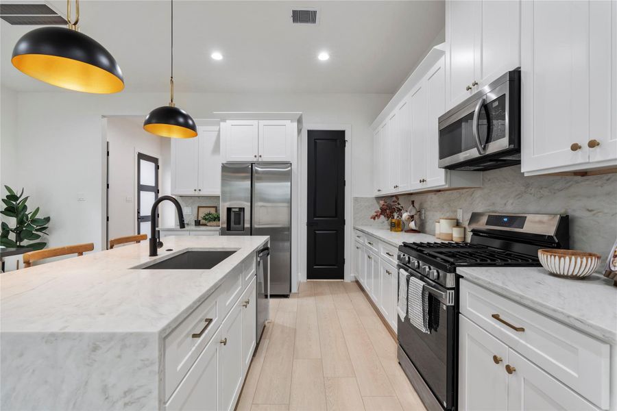 Chef’s kitchen featuring floor-to-ceiling cabinetry, quartz surfaces, and pantry access. Chef’s kitchen featuring floor-to-ceiling cabinetry, quartz surfaces, and pantry access.