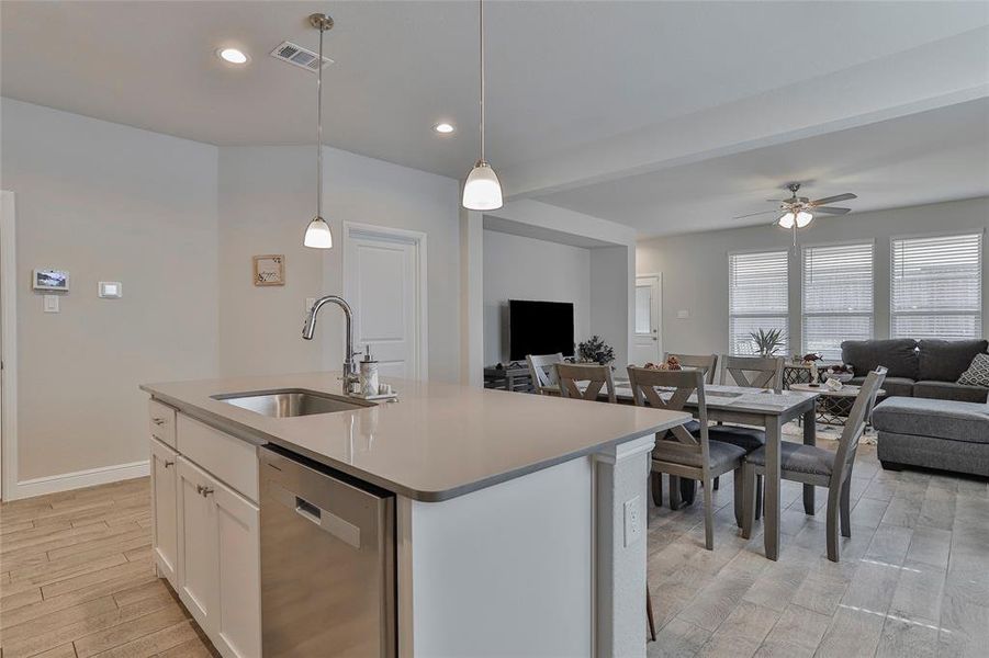 Kitchen featuring open floor plan, white cabinetry, dishwasher, light wood-style floors, and pendant lighting Kitchen featuring open floor plan, white cabinetry, dishwasher, light wood-style floors, and pendant lighting