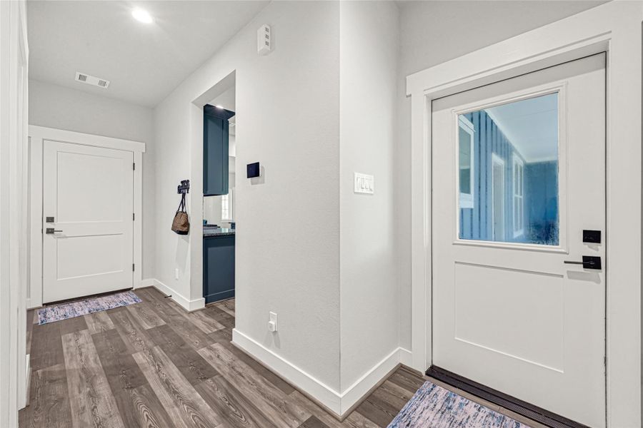 Hallway with access to garage, patio, laundry, half bath, and primary suite