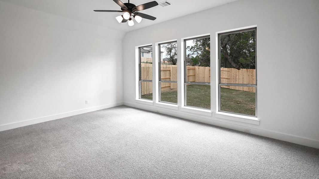 Carpeted empty room featuring plenty of natural light, baseboards, and a ceiling fan Carpeted empty room featuring plenty of natural light, baseboards, and a ceiling fan