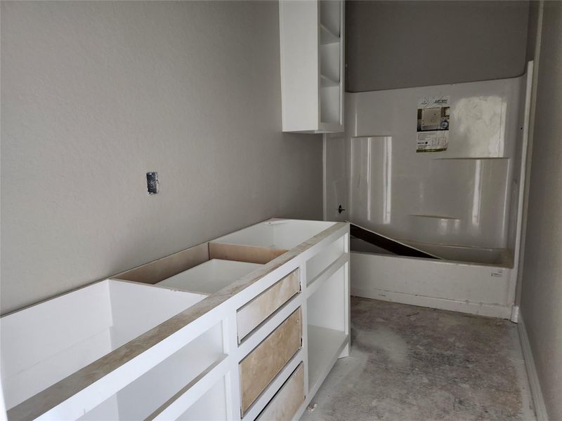 This photo shows a bathroom with a built-in bathtub and white cabinetry. The walls are painted a neutral color.