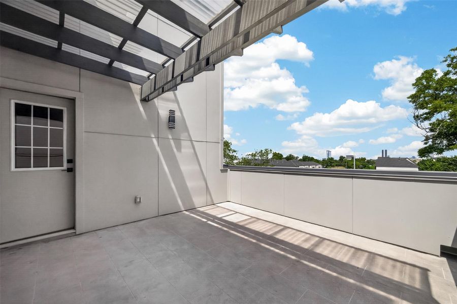 This photo showcases a spacious, modern rooftop terrace with a partial pergola, providing shade. The area features clean lines, light-colored tiles, and a wide-open view of the sky and surrounding greenery, making it ideal for relaxation or entertaining. This photo showcases a spacious, modern rooftop terrace with a partial pergola, providing shade. The area features clean lines, light-colored tiles, and a wide-open view of the sky and surrounding greenery, making it ideal for relaxation or entertaining.