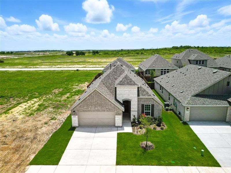 View of front of house featuring driveway, brick siding, an attached garage, and a shingled roof