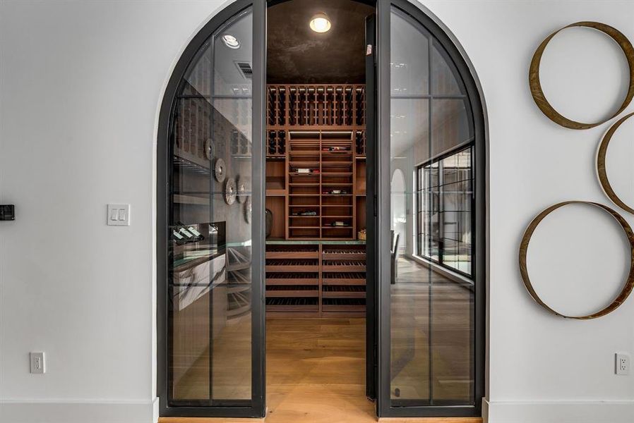 Wine room featuring a sauna / steam room, arched walkways, and light wood-style flooring