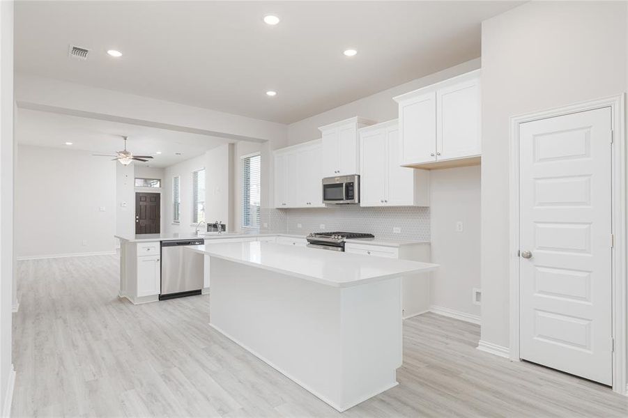 Kitchen with a kitchen island, white cabinetry, light hardwood / wood-style flooring, sink, and stainless steel appliances