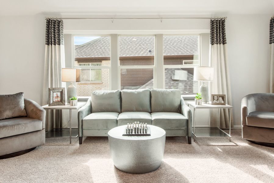 Living room with gray sofa, round coffee table, and large windows with patterned curtains