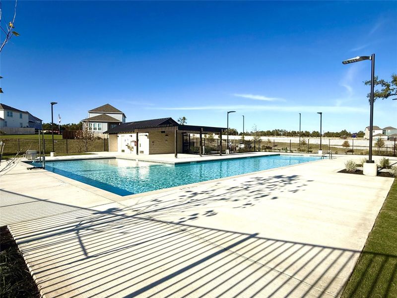 Community swimming pool featuring a rectangular shape and surrounding concrete decking