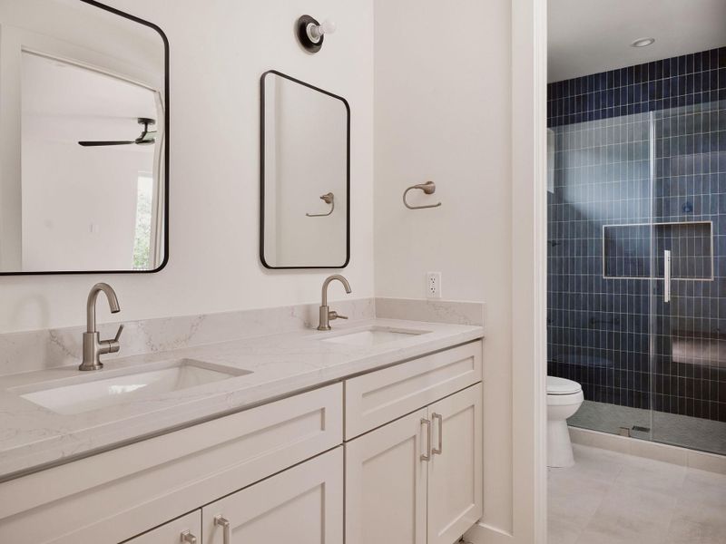 Bathroom featuring a dual vanity with light-toned cabinetry, integrated sinks, brushed nickel faucets, and light-toned countertops