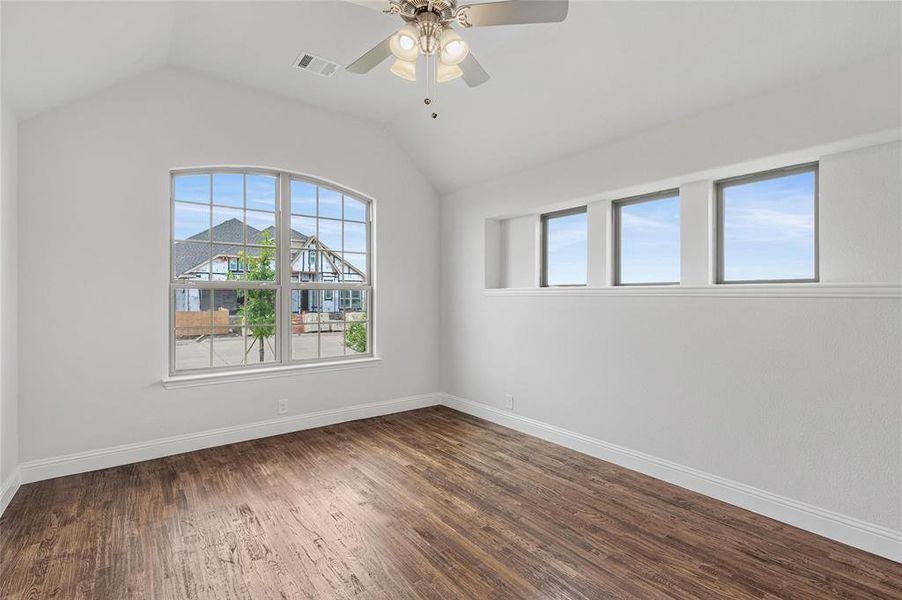 Spare room with lofted ceiling, dark wood-style flooring, plenty of natural light, and ceiling fan