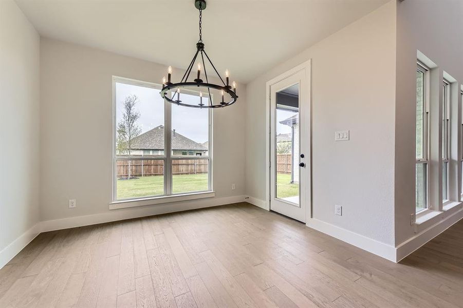 Unfurnished dining area featuring a chandelier, wood finished floors, and baseboards