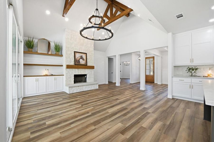 Unfurnished living room featuring a fireplace, hanging lights, and light wood-style floors