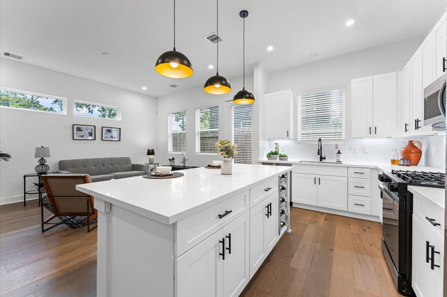 This centrally positioned kitchen island serves as a stylish anchor within the open-concept layout, offering clear sightlines to the dining area, living space, and the backyard beyond. Its placement encourages seamless interaction, whether prepping meals or entertaining guests, while natural light pours in through the nearby windows. The island’s sleek design and functional surface make it a hub of activity, framed by elegant finishes tying together comfort and sophistication.